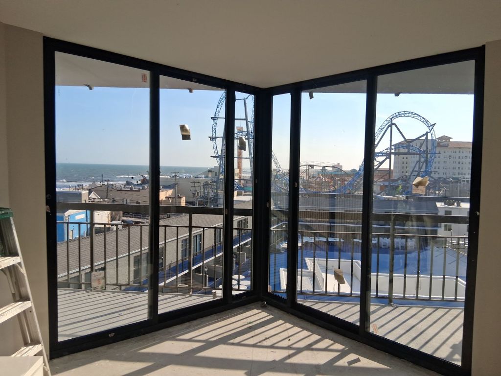 Corner black aluminum sliding glass door system with panoramic coastal boardwalk view