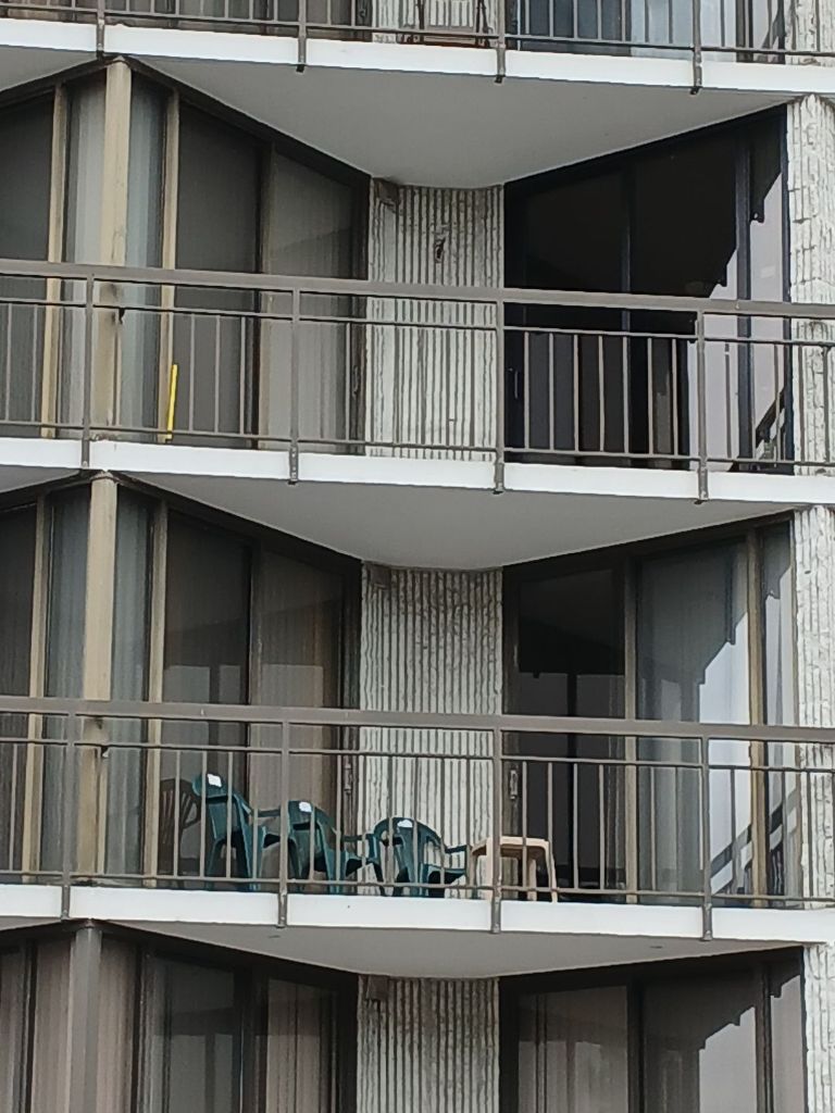 Ocean Colony balcony with dark aluminum sliding glass doors and coastal balcony furniture