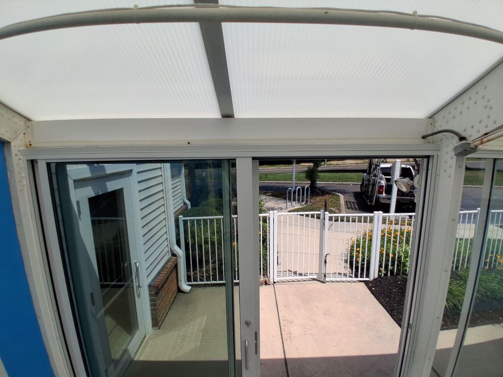 Pool enclosure interior view through white aluminum sliding glass doors to fenced patio